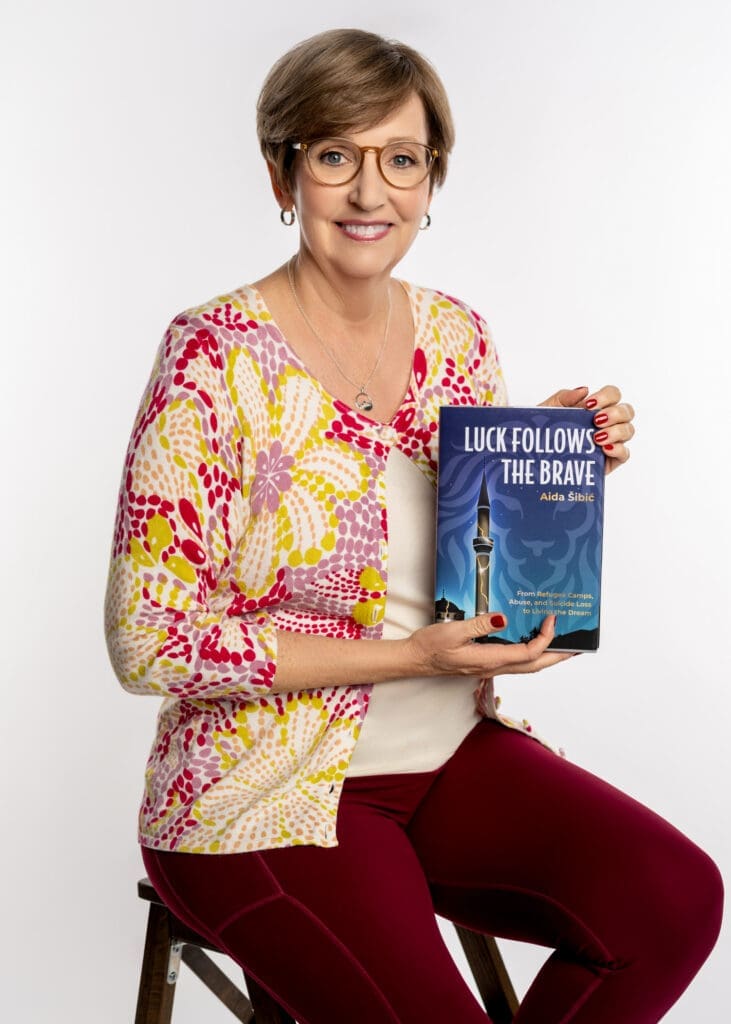 Laura Bush sitting on stool holding book 2 hands